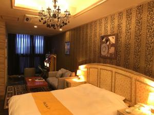 a bedroom with a bed and a couch and a chandelier at ホテルヴィラコスタ Adult Only 男塾ホテルグループ in Hikone