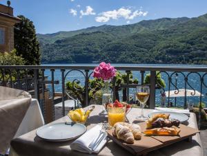 a table with food and glasses of wine on a balcony at Hotel Orso Bruno in Carate Urio