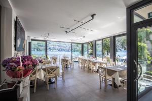 a dining room with tables and chairs and windows at Hotel Orso Bruno in Carate Urio