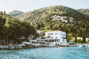 a house on the water in front of a mountain at The Durrell White House in Kalami