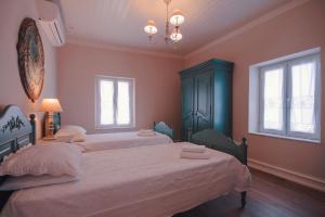 1 dormitorio con 2 camas y 2 ventanas en The Durrell White House en Kalámi