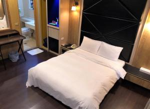 a bedroom with a large white bed with a black headboard at Guest Motel-Zhubei in Zhubei