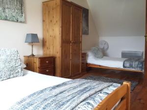 a bedroom with two beds and a wooden cabinet at Le Grenier, La Vieille Ferme in Ruffiac