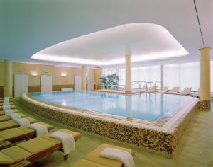 
a large room with a pool, chairs, and tables at Lindner Hotel Dom Residence in Cologne
