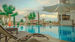 a pool at a resort with chairs and an umbrella at Parliament Palace Hotel in Khujand
