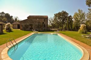 a swimming pool in front of a stone house at Villa Conte Gualtiero in Sarteano