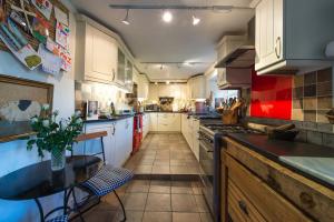 a large kitchen with white cabinets and a table at Church Cottage in Bath