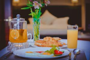 a table with a plate of food and a glass of orange juice at Parliament Palace Hotel in Khujand