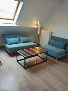 a living room with two blue couches and a coffee table at Greenfee vakantieappartement in De Haan