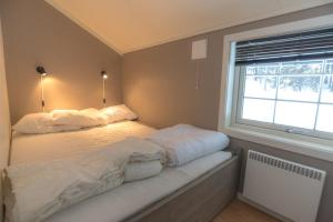 a bedroom with a bed with white sheets and a window at Fjelltun 6-sengs in Trysil