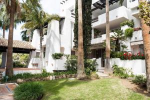 a view of the front of a building with palm trees at Marina Puente Romano - Groundfloor - 3 Bedrooms in Marbella