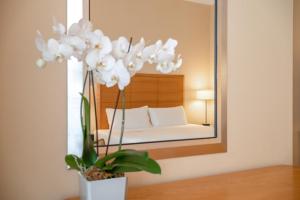 a bedroom with a bed and a mirror with white flowers at Hotel Capo d´África – Colosseo in Rome