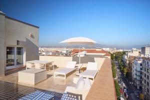 balcón con muebles blancos y sombrilla en Tandem Soho Suites, en Málaga