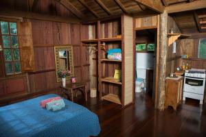 a bedroom with a blue bed and a kitchen at Chalé Candeia no Matutu in Aiuruoca