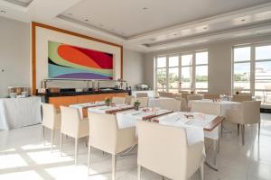 a restaurant with white tables and chairs and a painting at Hotel Capo d´África – Colosseo in Rome