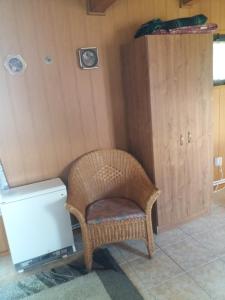 une chaise en osier dans une pièce avec une armoire dans l'établissement Chata Dvorečná, à Loučovice