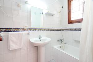 a white bathroom with a sink and a bath tub at Hostal Las Nieves in Ibiza Town