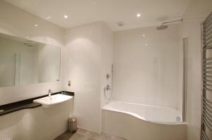a white bath tub sitting next to a white sink at La Fregate Hotel in St. Peter Port