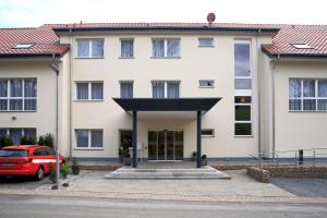 een gebouw met een rode auto ervoor geparkeerd bij Hotel Grünwalde in Halle Westfalen