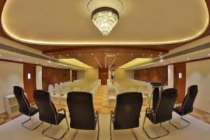 a conference room with white chairs and a chandelier at Annai Resorts & Spa in Kanyakumari