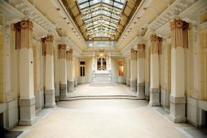 an empty hallway in a building with columns and a glass ceiling at Maverick Downtown in Budapest