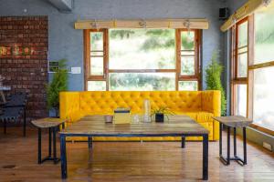 a yellow couch in a room with a table at The Hosteller Mcleodganj, Upper Bhagsu in McLeod Ganj