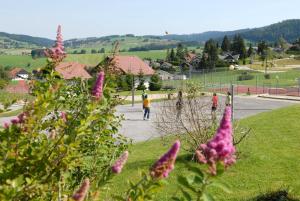 a group of people walking down a street with purple flowers at Azureva Métabief in Métabief