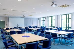 a conference room with tables and chairs and a screen at LEAG Konferenzcenter Schulungs- und Tagungshotel im Spreewald in Lübbenau