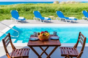 a table with a bowl of fruit next to a pool at Diagoras & Attalos Villas in Phanaes