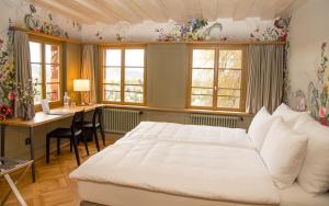 a bedroom with a bed and a desk and windows at Hotel Restaurant Falkenburg in St. Gallen