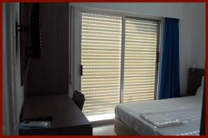 a bedroom with a bed and a window with blinds at St. George Rent Rooms in Larnaca