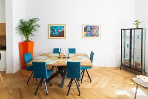 a dining room with a wooden table and blue chairs at TCF Home - Modern Apartments 2 in Kraków