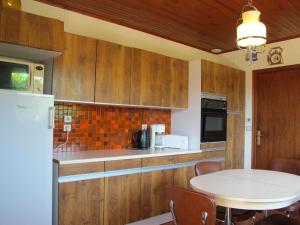 a kitchen with wooden cabinets and a white table at Holiday Home Roitelet by Interhome in Mimizan-Plage