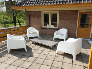 four white chairs and a bench on a patio at Studio in Stijl in Apeldoorn