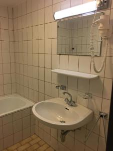 een badkamer met een wastafel, een spiegel en een bad bij Sporthotel am Ötscher in Lackenhof