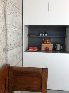 a kitchen with white cabinets and a wooden bench at Da La Babi B&B in Arco