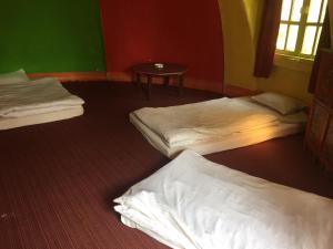 a room with three beds and a table in it at Hotel At The End Of The Universe in Nagarkot