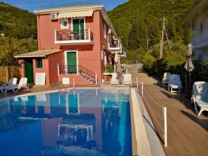a large swimming pool next to a pink house at Stella 's Sea Front Apartments in Yénion