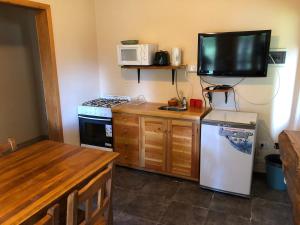 a small kitchen with a refrigerator and a tv on the wall at Hosteria Futalaufquen in Parque Nacional Los Alerces