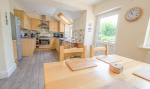 a kitchen with a table and a clock on the wall at Cloudbreak Braunton, Sleeps 8 - Hot Tub hire - Dog Friendly in Braunton