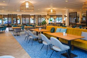 - un restaurant avec des tables, des chaises et un canapé dans l'établissement Hotel Boschrand, à De Koog