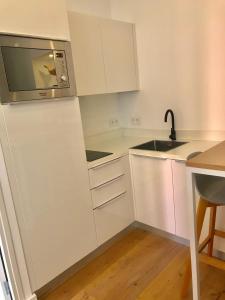 uma cozinha branca com uma pia e um micro-ondas em Appart Hotel Garibaldi em Nice mais 11 fotografias