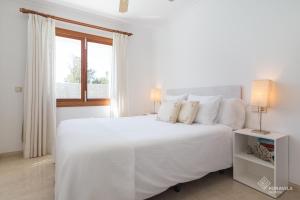 a white bedroom with a white bed and a window at Berganti in Port d'Alcudia +44 photos