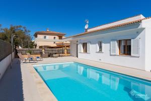 a villa with a swimming pool in front of a house at Berganti in Port d'Alcudia