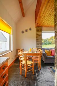een eetkamer met een tafel en stoelen en een bank bij Butterfly Cottage in Achill
