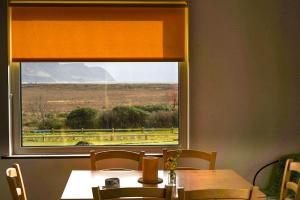 a table and a window with a view of a field at Butterfly Cottage in Achill