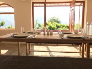 a wooden table with plates and glasses on top of it at Enchanted Hills Farmstay in Mukteshwar