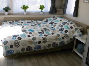 a bed with a comforter on it in a bedroom at Chalet Joleen IJmuiden aan zee, vlakbij het strand in IJmuiden
