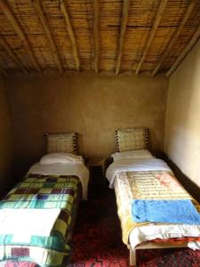 two beds in the corner of a room at Auberge Tigida in Mhamid