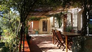 een patio met een tafel en stoelen in een tuin bij Les Oliviers in Moustiers-Sainte-Marie